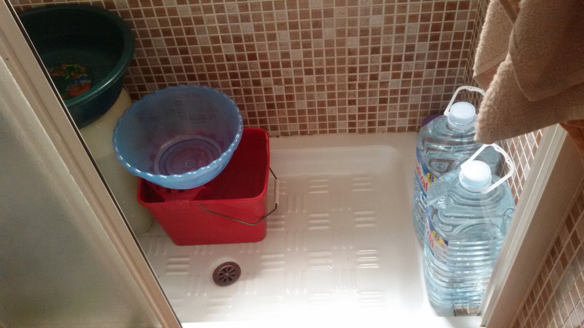 Plato de ducha preparado con garrafas y cubos de agua