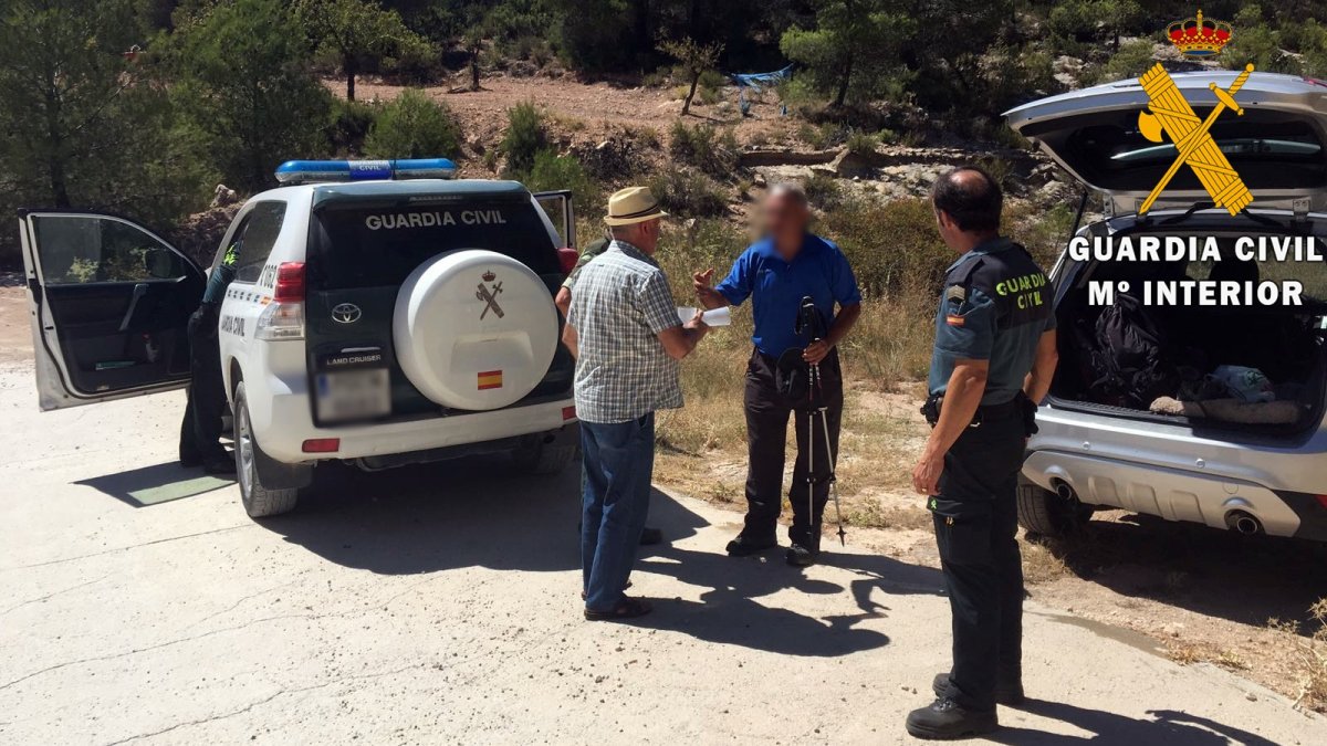Miembros de la Guardia Civil con uno de los senderistas.