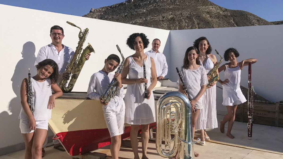 Las familias García Garrido y Jaramillo Garrido posan con sus instrumentos junto a la barca con la que el abuelo Justo Garrido salía a pescar en Las