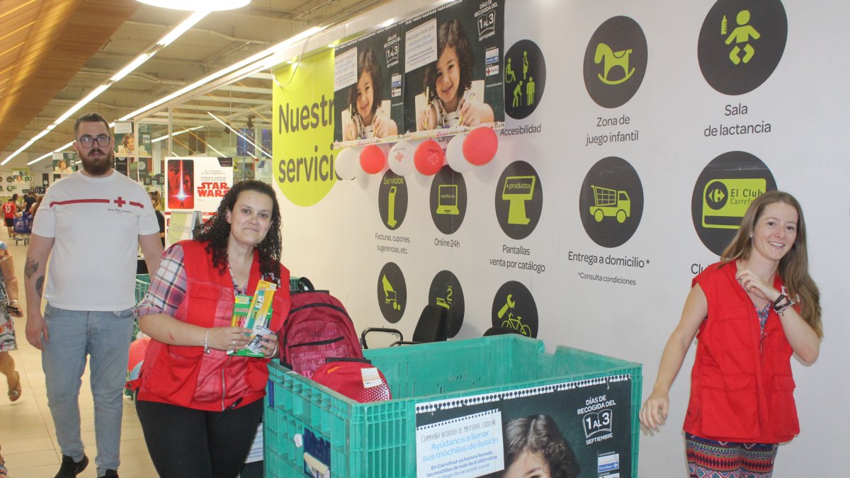 Emi Rubio, técnico de juventud de Cruz Roja en Almería;?junto a Kodro y Elena, voluntarios de Cruz Roja en Almería, depositando las mochilas donadas.