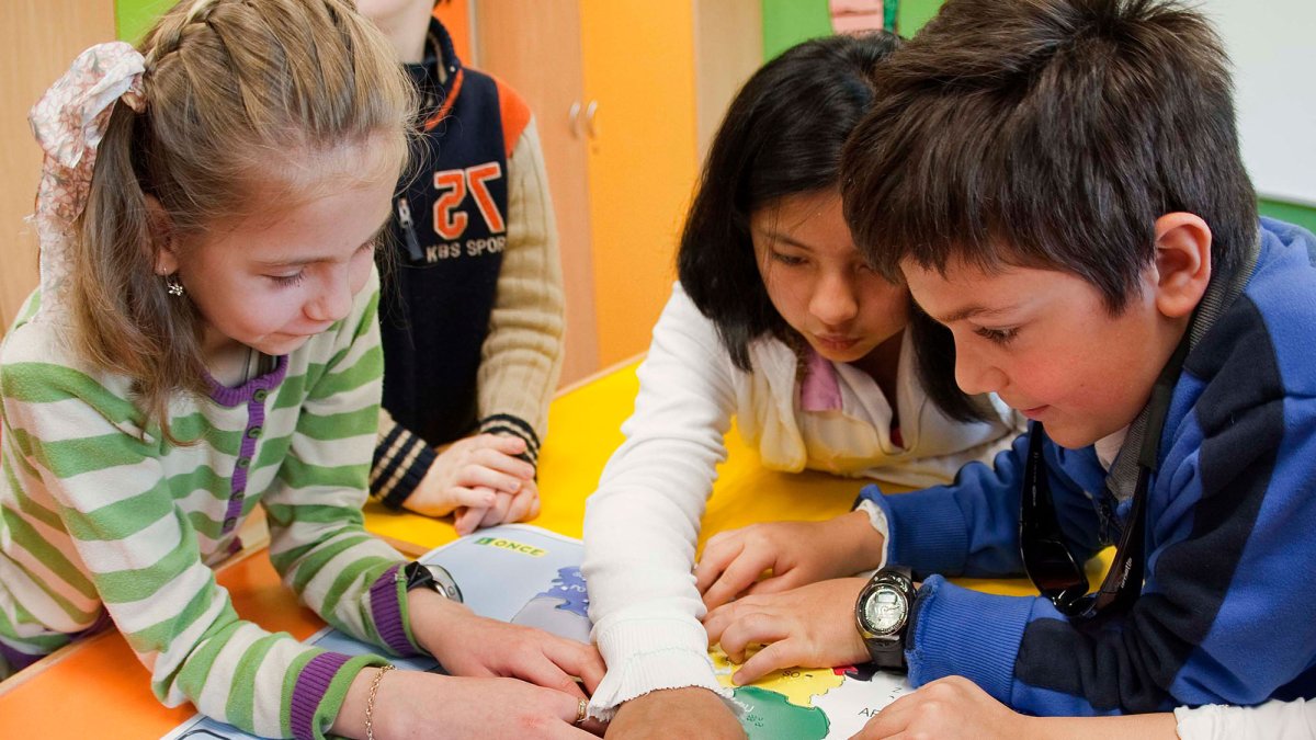 Varios niños reconocen un plano en relieve y braille.