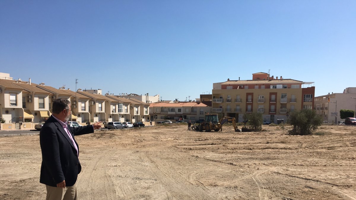 El alcalde junto al terreno que se convertirá en una zona verde con máquinas realizado tareas de limpieza.