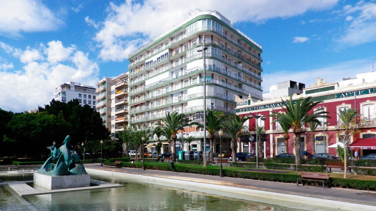 La fuente de los delfines precede a los bloques de pisos que miran hacia el puerto.