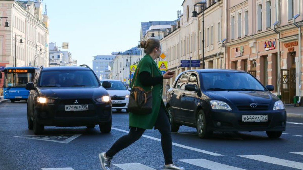 Una mujer cruza la carretera con el teléfono móvil en su mano. /Getty Images
