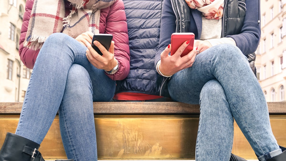 Dos chicas revisan mensajes en sus teléfonos móviles.