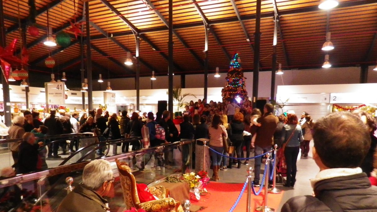 Visitantes del mercado asisten a un concierto de villancicos.