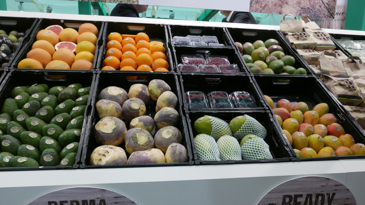 Stand con productos hortofrutícolas y una etiqueta de producción bajo técnicas de permacultura.