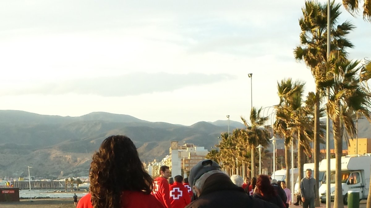 Una voluntaria con un anciano por el Paseo Marítimo.