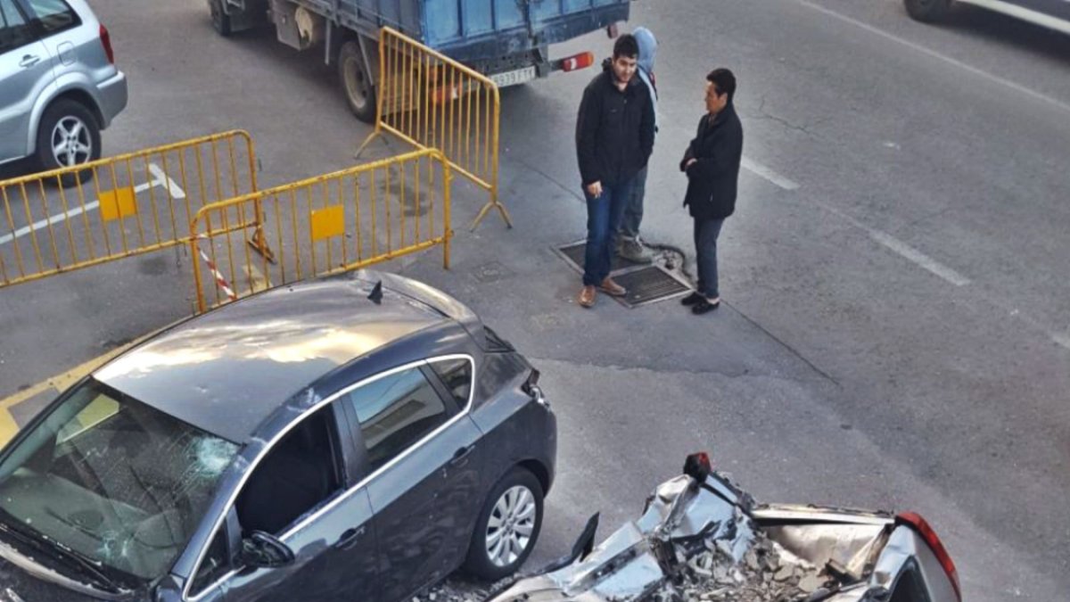 Estado de uno de los vehículos tras caerle encima parte de la fachada.