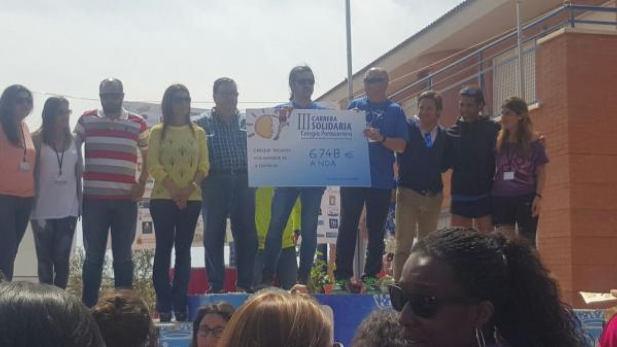 El director del Colegio Portocarrero, José Manuel Martínez, entrega al gerente de ANDA, José Ferrer el talón solidario en presencia de los concejale