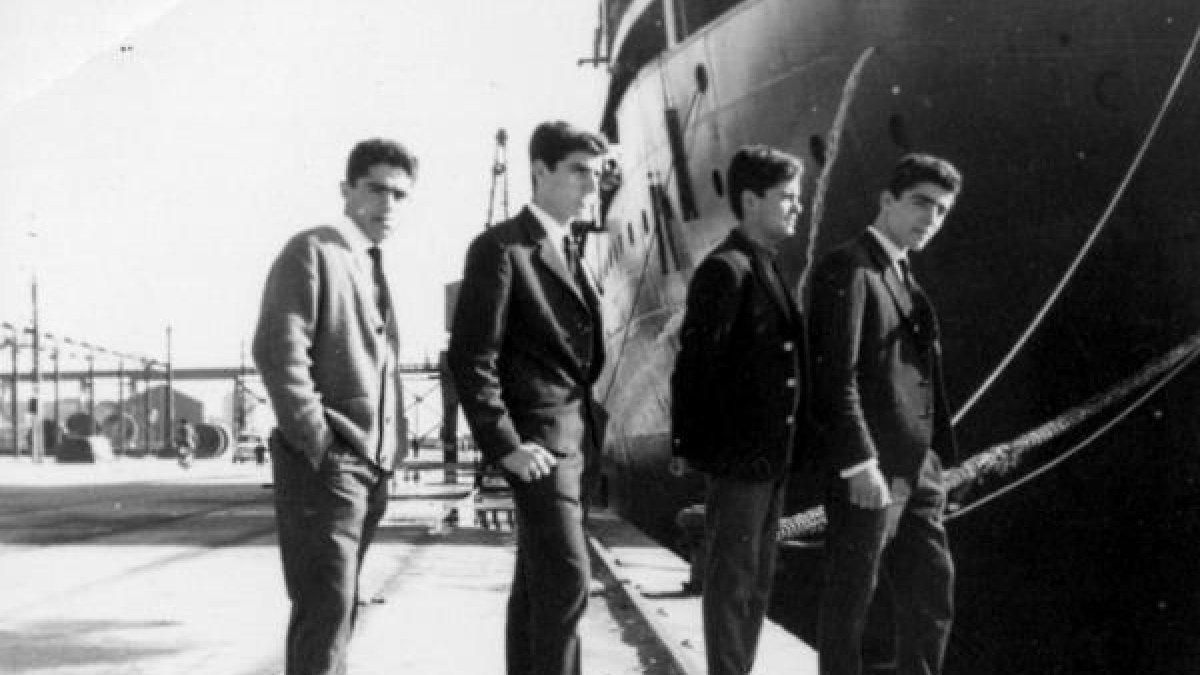 Cuatro amigos posando como los Beatles en una mañana de domingo en el puerto