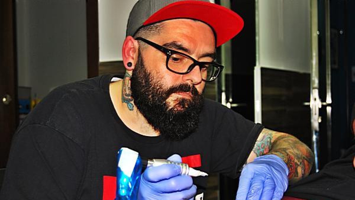 David Hernández Guerrero, Coco Guerrero en la profesión, tatúa el muslo de un cliente mientras va limpiando los rastros de sangre.