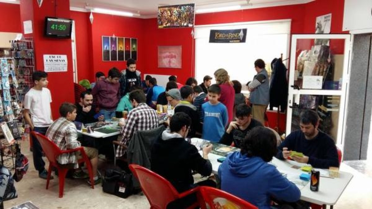 Varias personas, de todas las edades, reunidos  jugando a las cartas ‘Magic.’