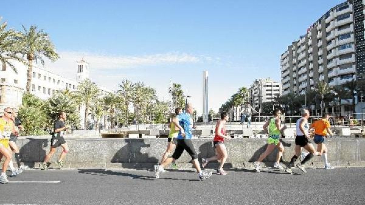 Corredores cruzan La Rambla a la altura de Las Almadrabillas en el marco de la Media Maratón de Almería.