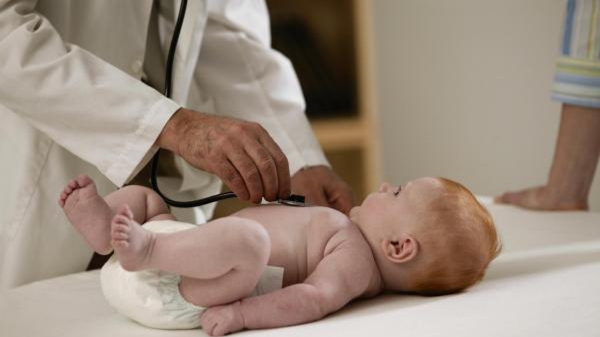 Un pediatra ausculta a un bebé en consulta.