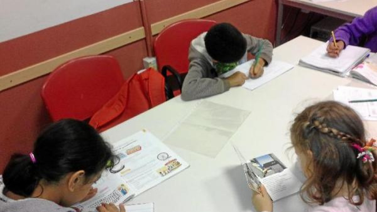 Niños del programa de apoyo escolar de Cruz Roja hacen la tarea en el aula de formación.