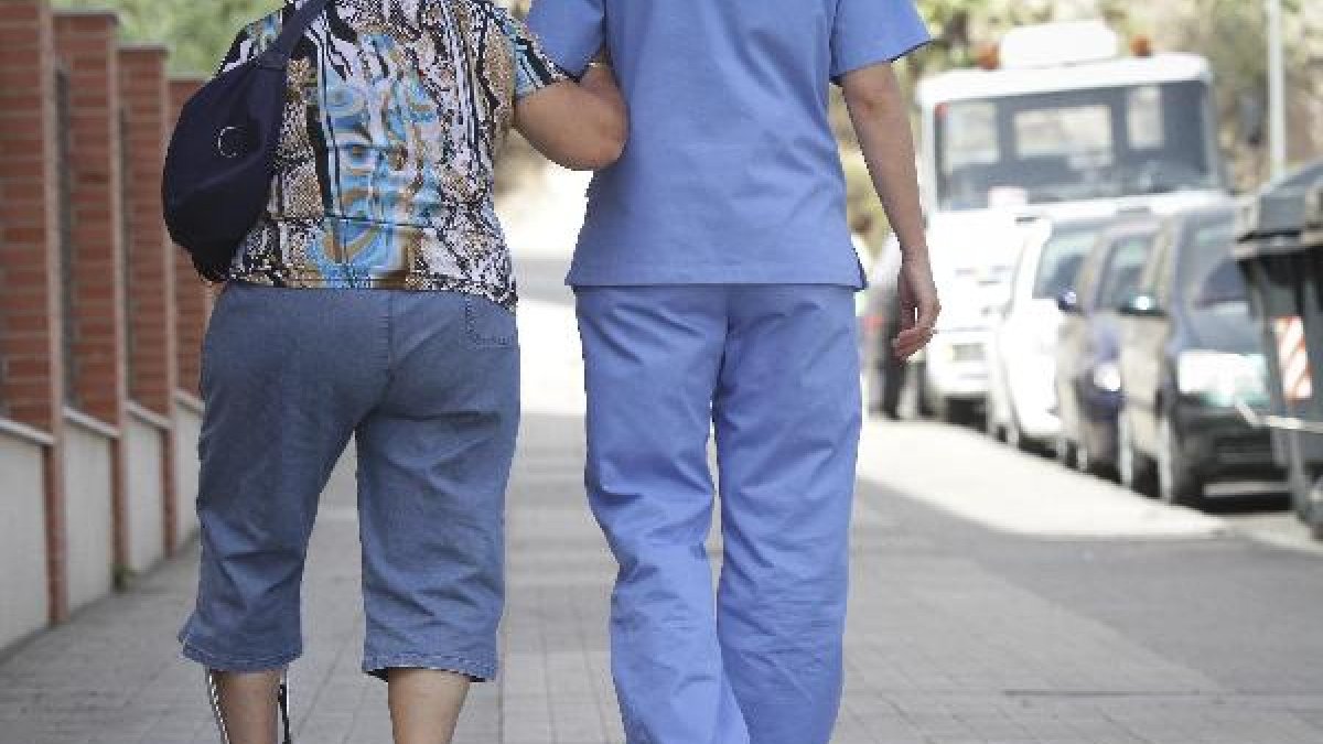 Una sanitaria asiste a una mujer en las cercanías de un centro de salud.