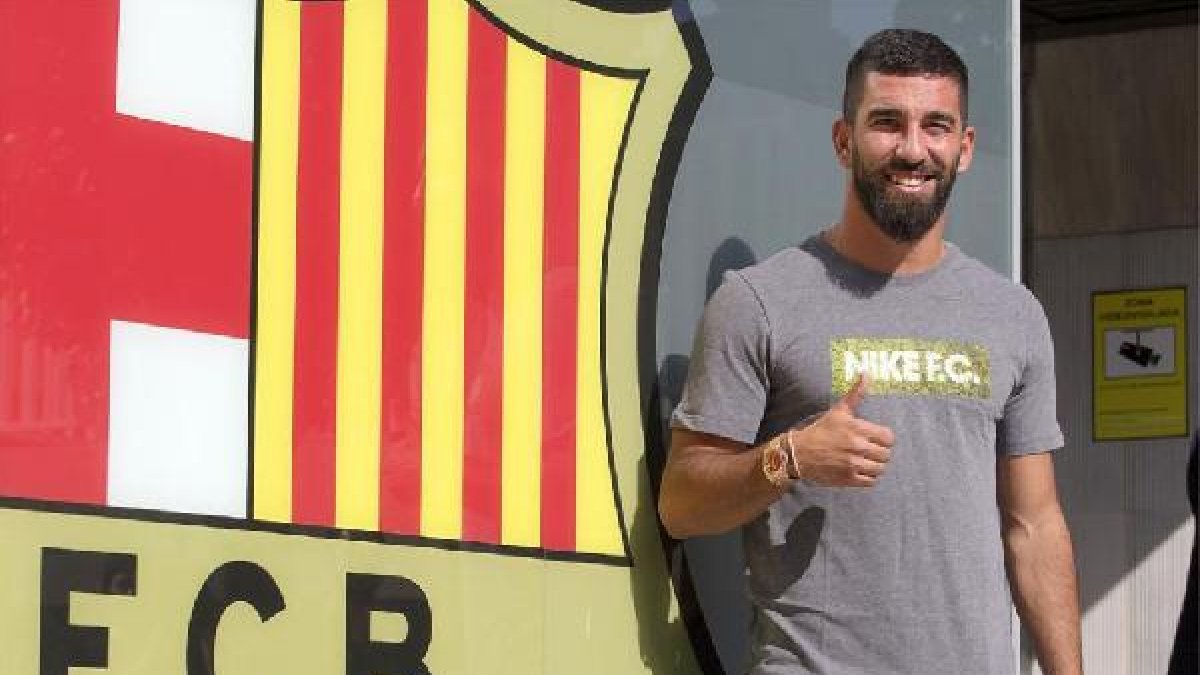 Arda Turan junto al escudo del FC Barcelona.