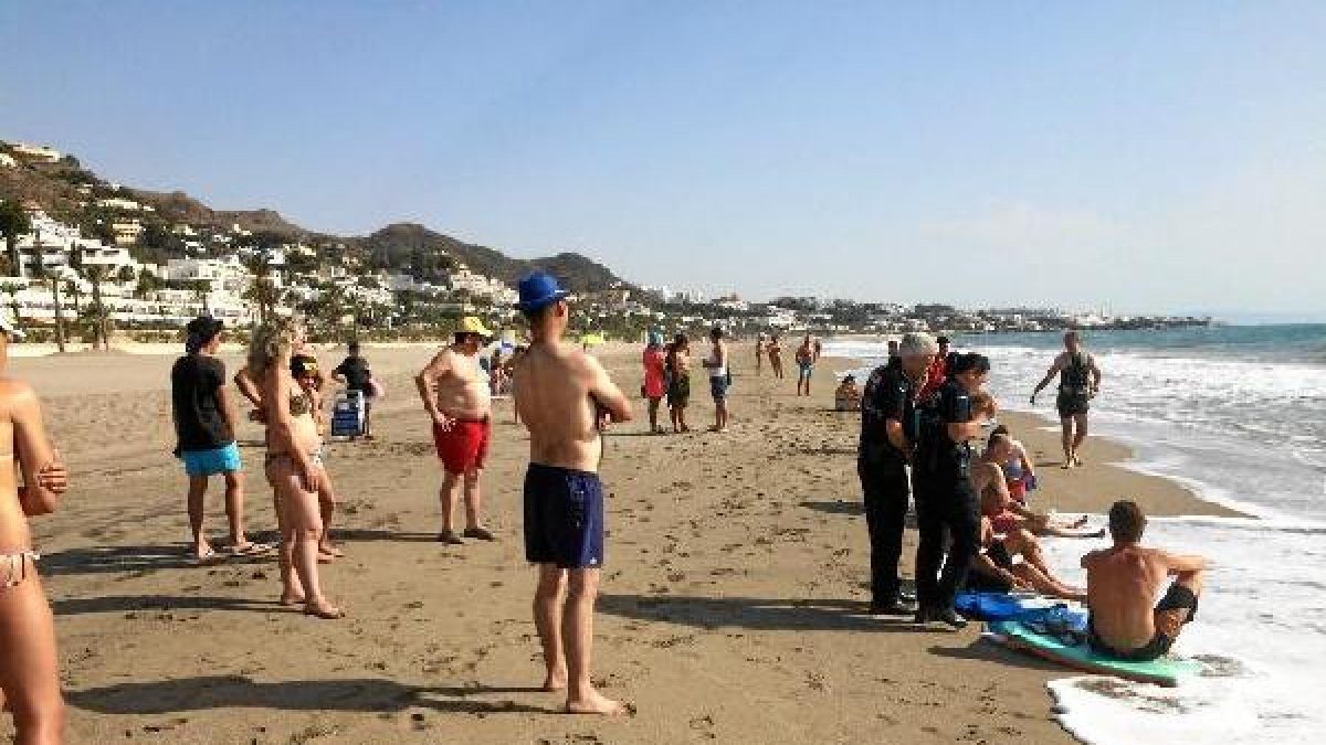 La Policía junto a los bañistas tras ser rescatados.
