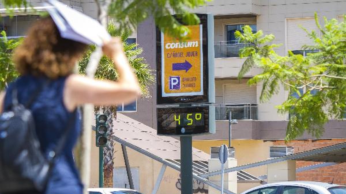 Una mujer trata de taparse del sol ante un termómetro que marca 45ºC.