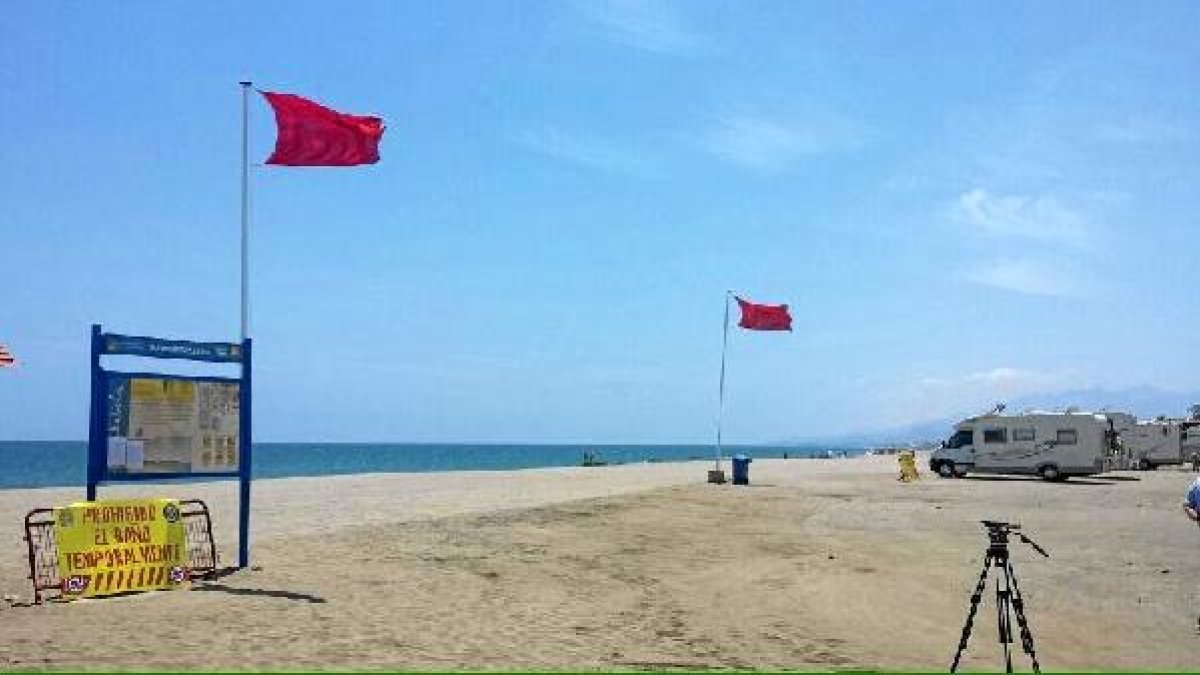 Banderas rojas y un cartel que prohíben el baño en una de las playas afectadas de Cuevas.