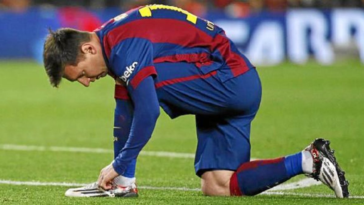 Leo Messi se ata la bota de su pierna buena.