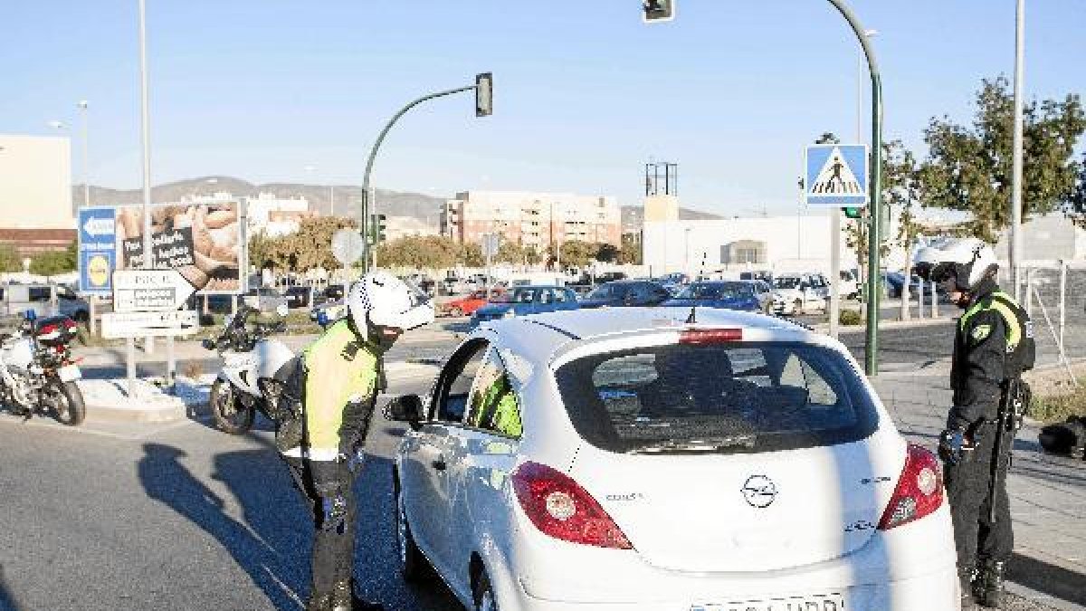 Efectivos de la Policía Local registran un vehículo en un control a la entrada del barrio.