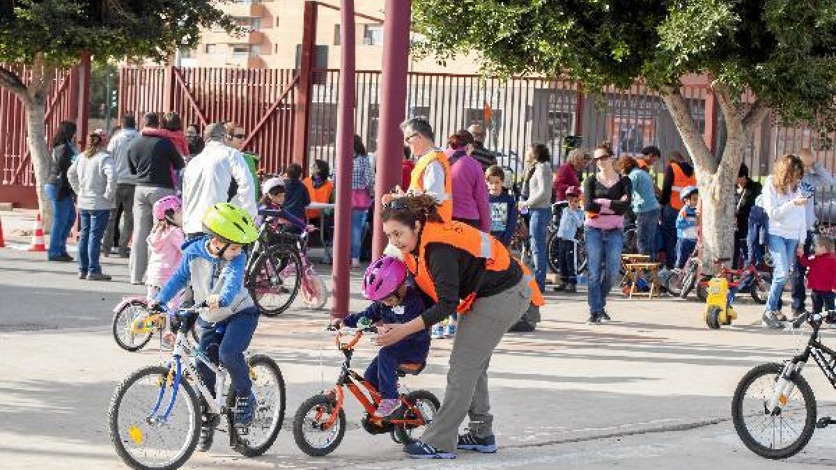 Un voluntario de Alpedal enseña a una niña a montar en bicicleta.
