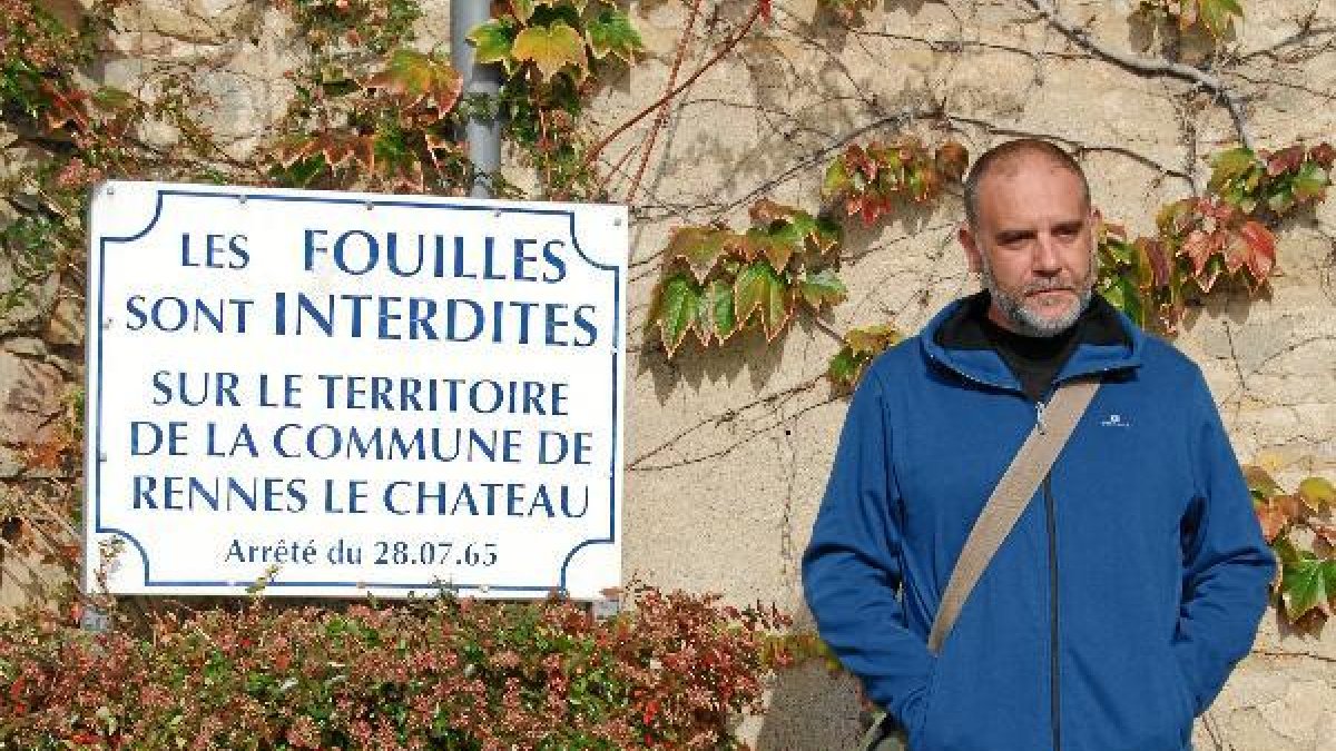 Óscar Fábrega, junto al cartel de Rennes-le-Château, en Francia, en el que se prohíbe excavar.