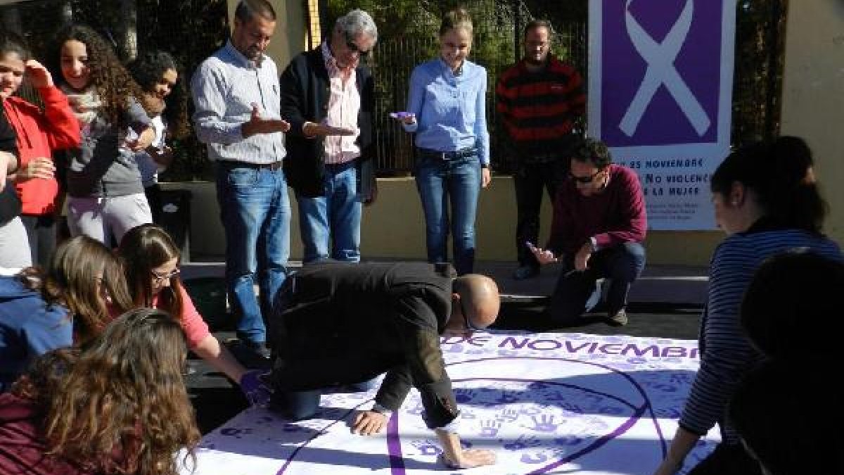 Alcalde y jóvenes plasman sus manos en la pancarta.