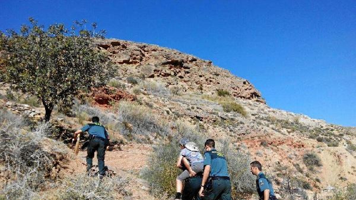 Un agente trasnporta sobre su espalda a la mujer lesionada.