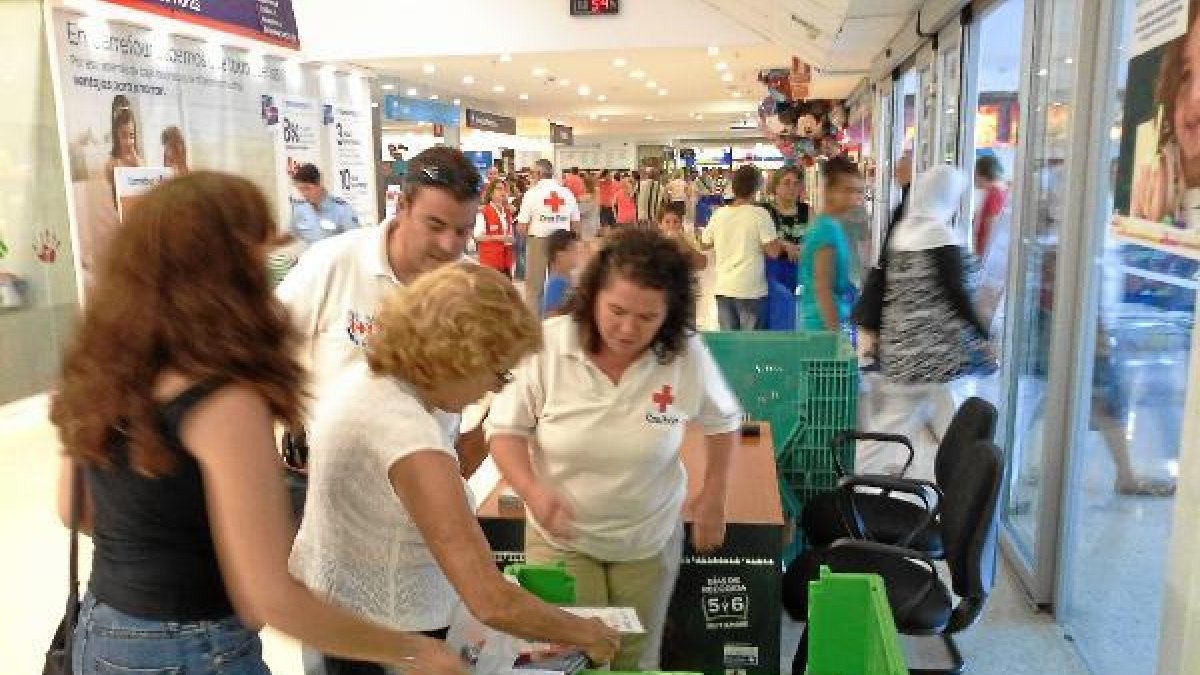Una familia entregando material escolar en el stand de Cruz Roja en el Carrefour de la capital.