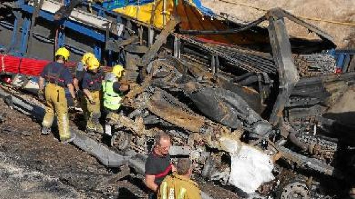 Los bomberos trabajan para sacar la furgoneta que quedó aplastada por el camión.tyle>.apqj