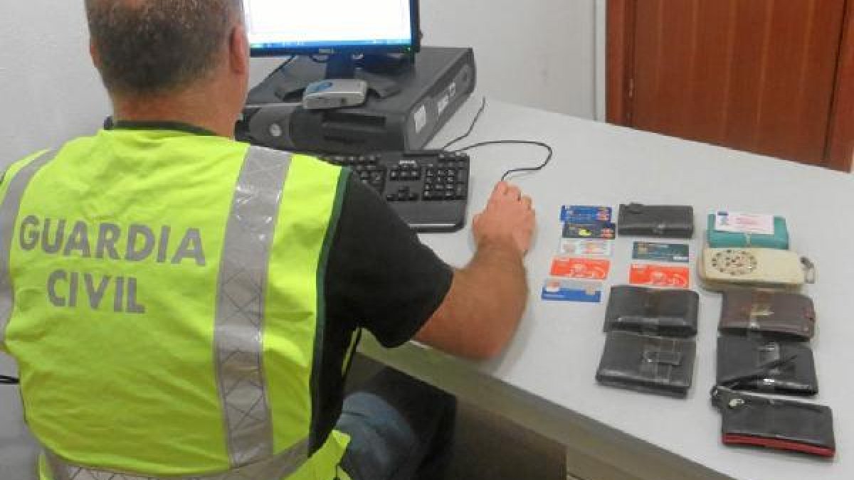 Un agente junto a carteras intervenidas a los detenidos.e;clip:
