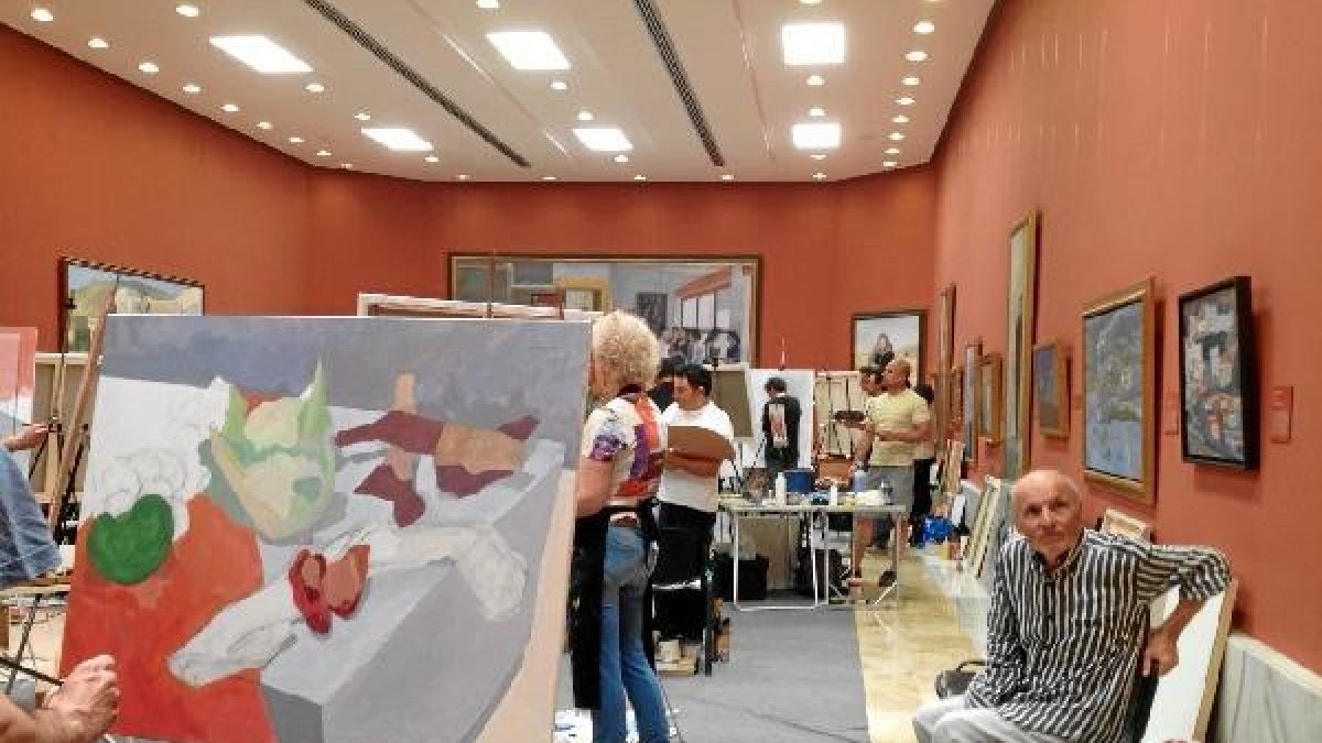 Antonio López, sentado en una silla y contemplando apacible cómo trabajaban en los lienzos sus avent