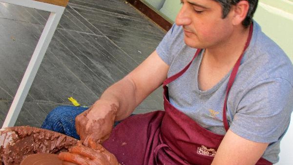 Uno de los artesanos que acudieron a la cita mientras elabora una hucha.tyle>.apqj{positio