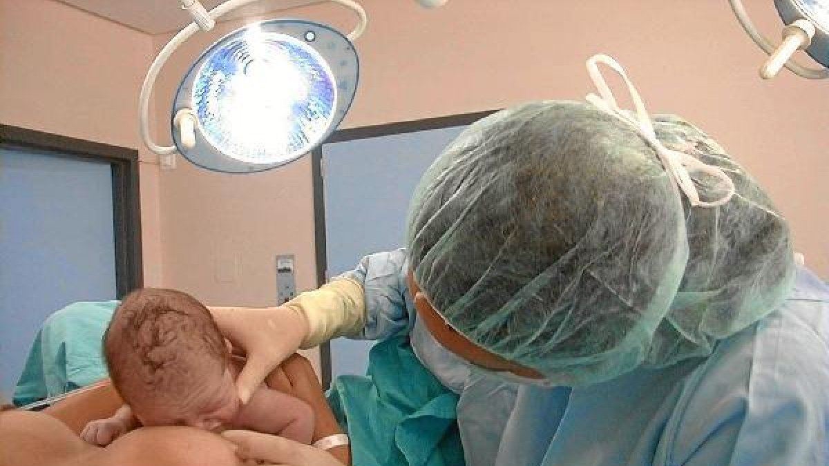 Un bebé recién nacido sobre el vientre de su madre.e;clip:rect(