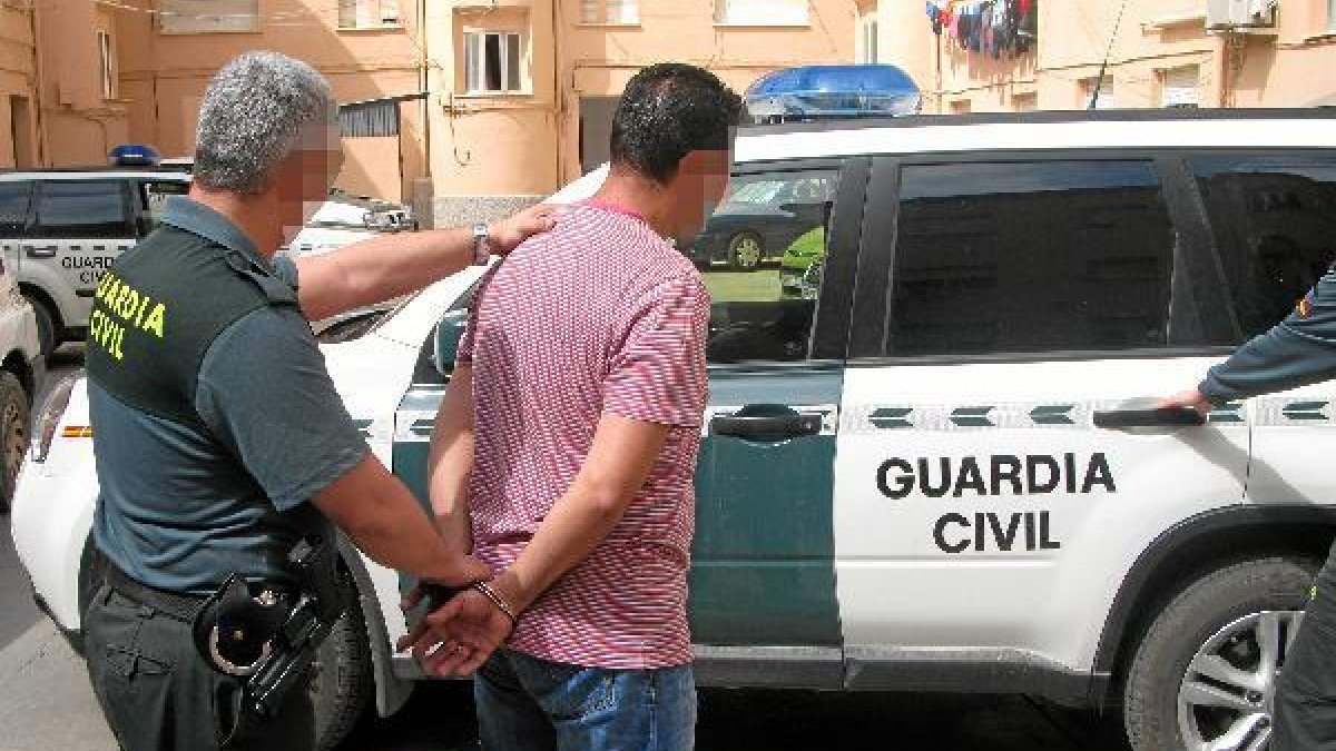 Un agente conduce al coche patrulla a uno de los detenidos. e;c