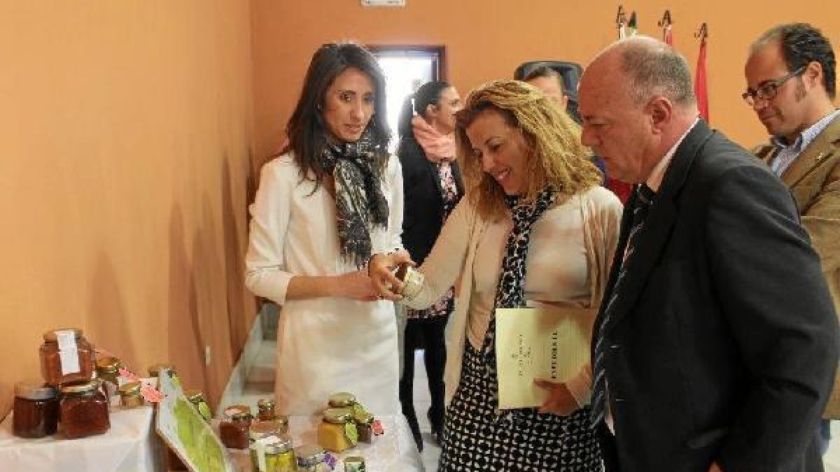 La delegada y el alcalde observan las conservas realizadas por las alumnas.tyle>.apqj{posi