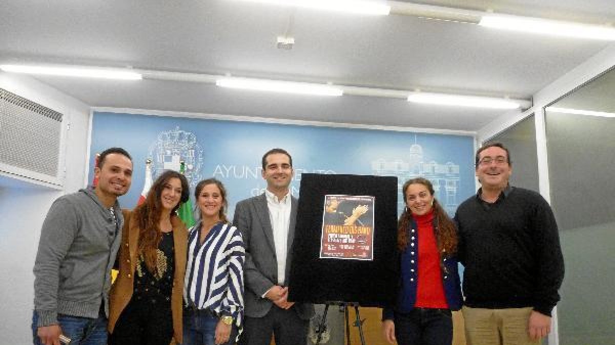 Foto de falmilia de varios organizadores y artistas con el cartel del concierto.tyle>.apqj