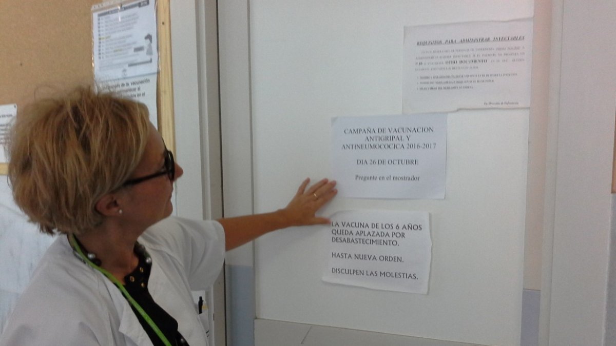 Una sanitaria indica uno de los carteles que anuncian la vacunación.