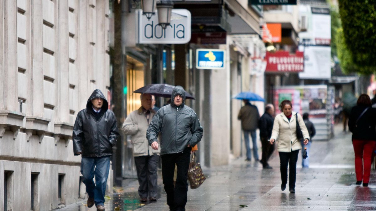 Unos ciudadanos caminan por el centro de la ciudad en una fria jornada de lluvia