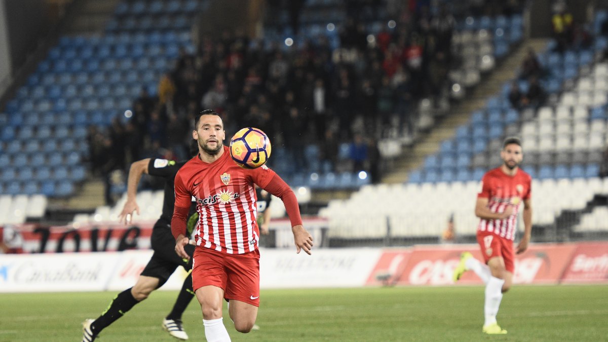 Quique mira la pelota y Puertas corre a su lado hacia el área.