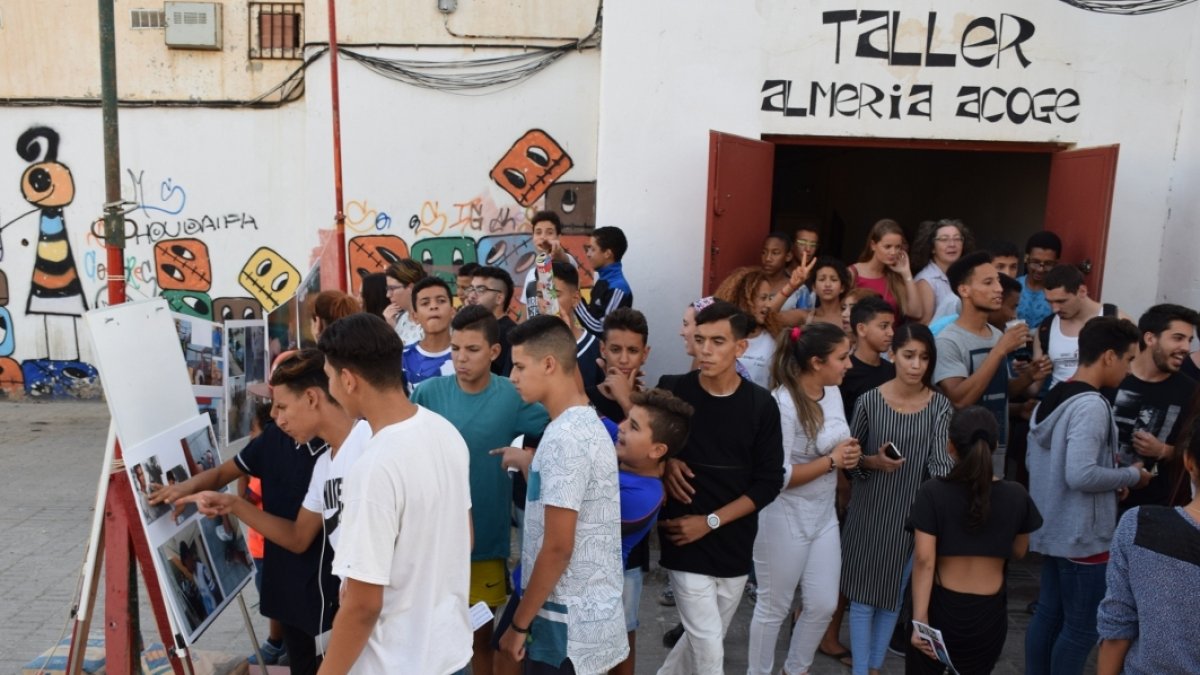 Vecinos visitan la exposición fotográfica impulsada por Almería Acoge en su taller del barrio de El Puche.