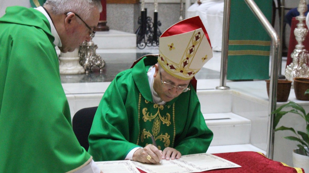 Adolfo González Montes firmando el acta de la bendición, junto al párroco, Francisco Salazar.