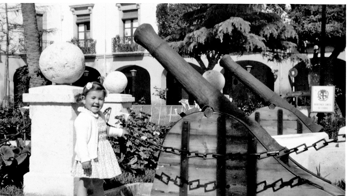 Una niña posa junto a los viejos cañones.