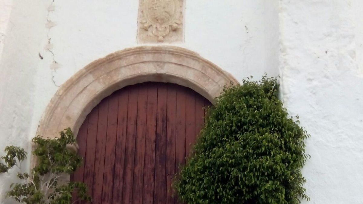 Flores y velas dejadas por vecinos, ante la puerta cerrada de la iglesia de Huebro.
