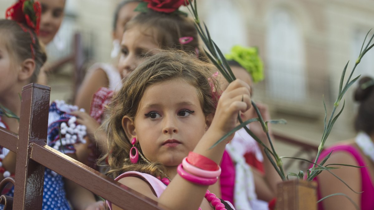 Una pequeña se prepara para lanzar claveles desde su carroza.