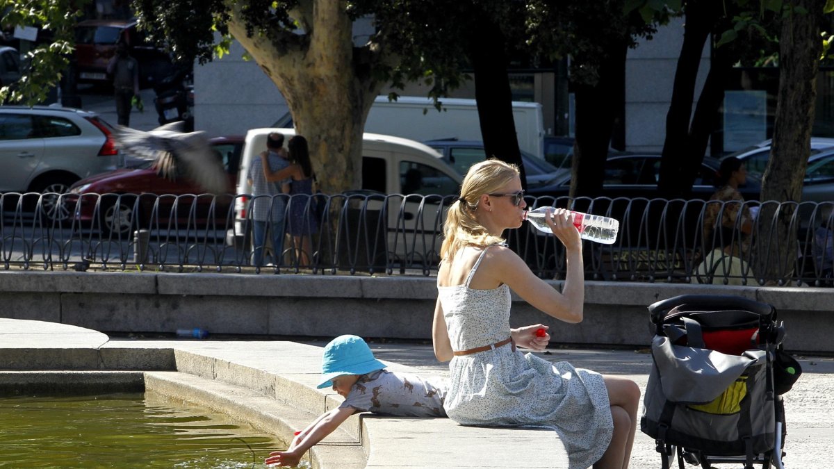 Una mujer combate el calor bebiendo agua.