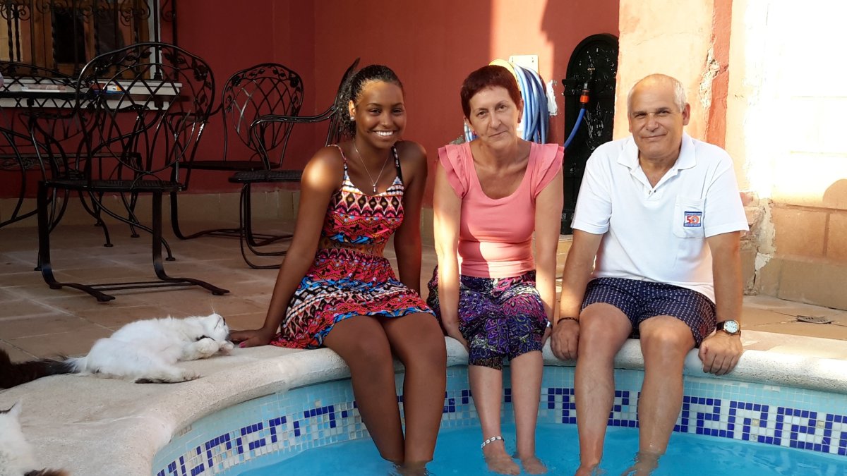 Hanna con sus padres de acogida, Teo y Jesús, se refrescan en la piscina de la vivienda que la familia tiene en Huércal de Almería, donde viven.